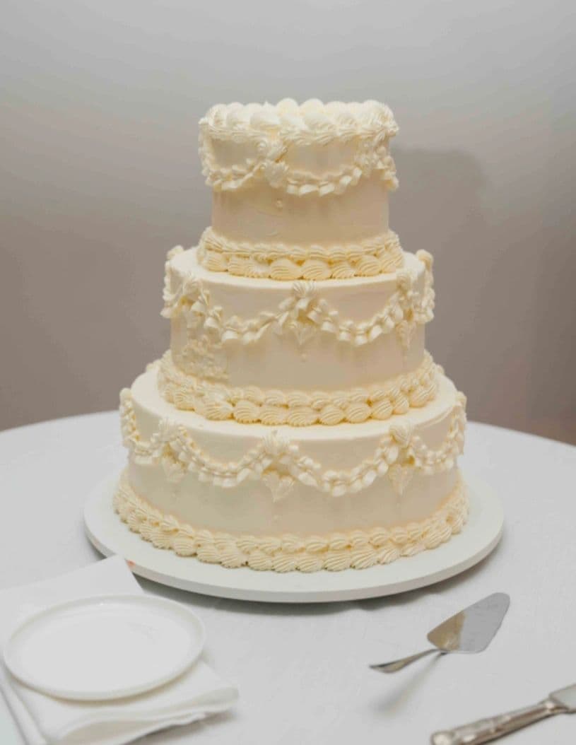 White wedding cake with piped lace and gold detailing