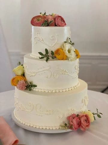 Three-tier white wedding cake with peach and apricot florals