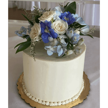 Single-tier white cake crowned with blue and white flowers
