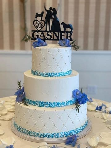Three-tier white cake with blue florals and a monogram topper