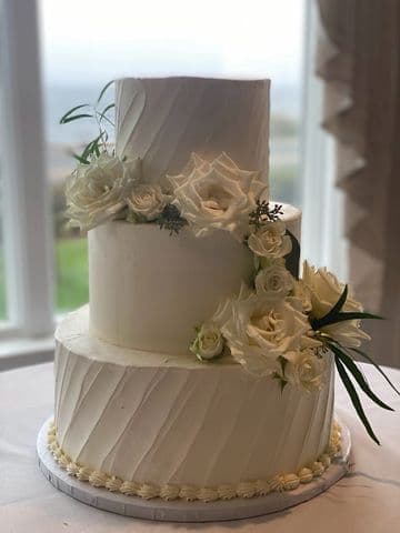 Two-tier white buttercream wedding cake dressed with garden roses and eucalyptus