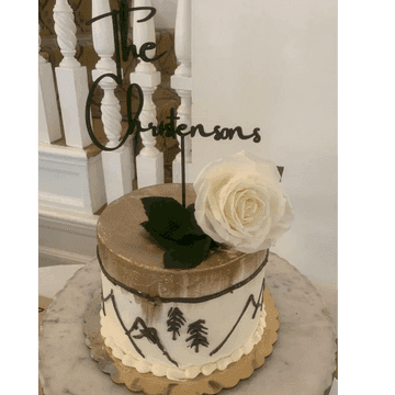 White wedding cake with a single rose and a script wire topper