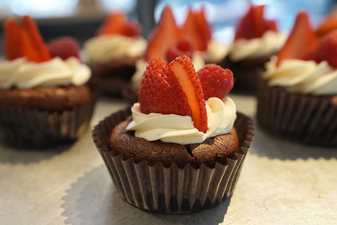 A chocolate cupcake with a cream swirl and a fanned strawberry