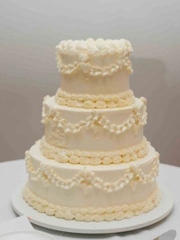 Three-tier white cake with piped lace scallops and sugar pearls