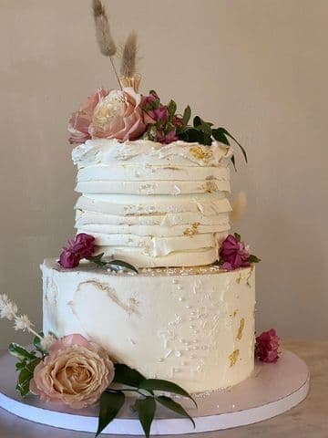Semi-naked buttercream cake with pink roses and a gold drip