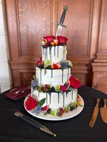 Tiered white cake with a berry drip and fresh fruit