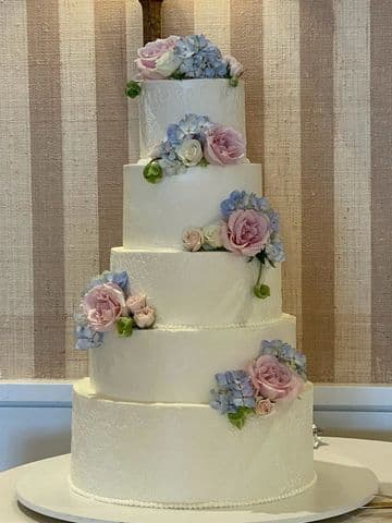 Three-tier white wedding cake with pastel sugar flowers