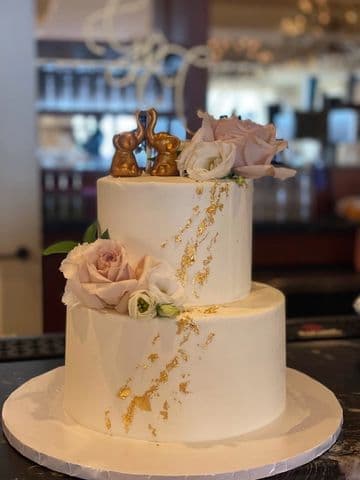 Three-tier blush wedding cake with roses and a gold drip