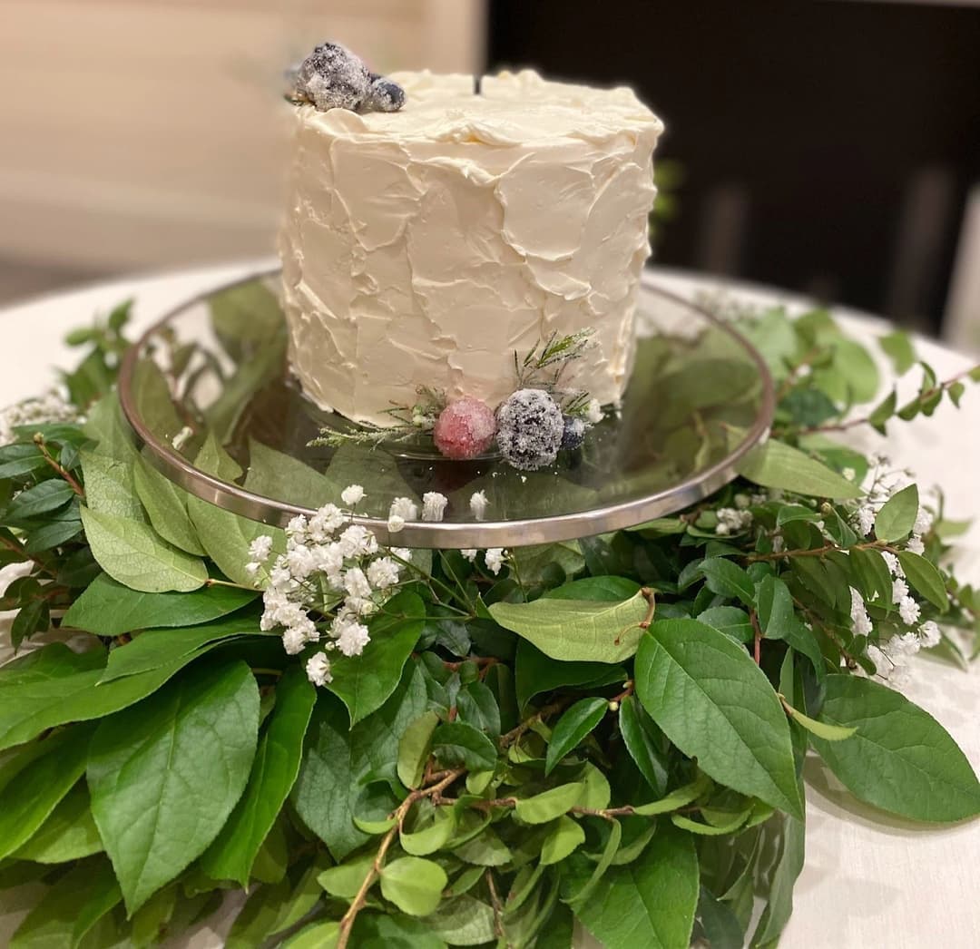 White frosted cake plated on a bed of fresh greens