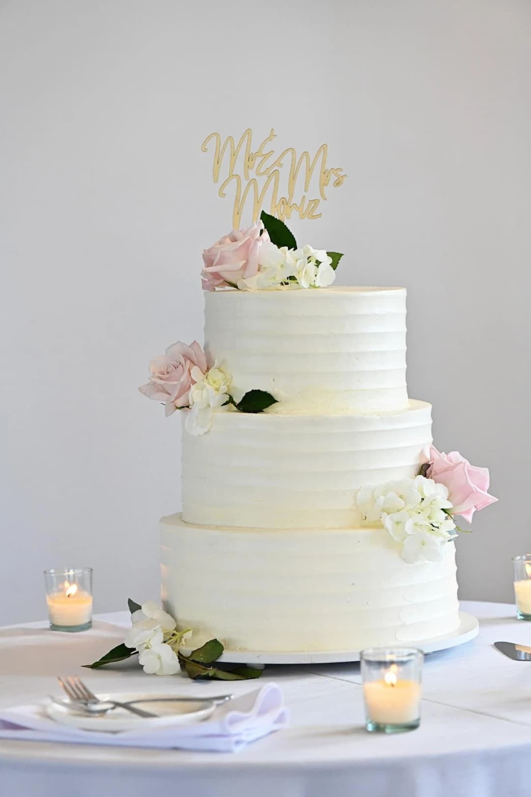 White tiered wedding cake with soft pink blooms