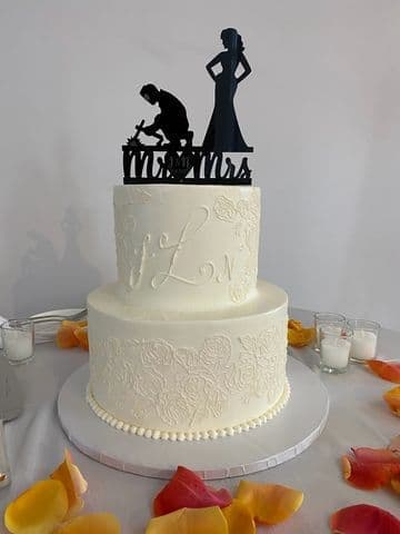 White lace-piped cake with a black silhouette couple topper