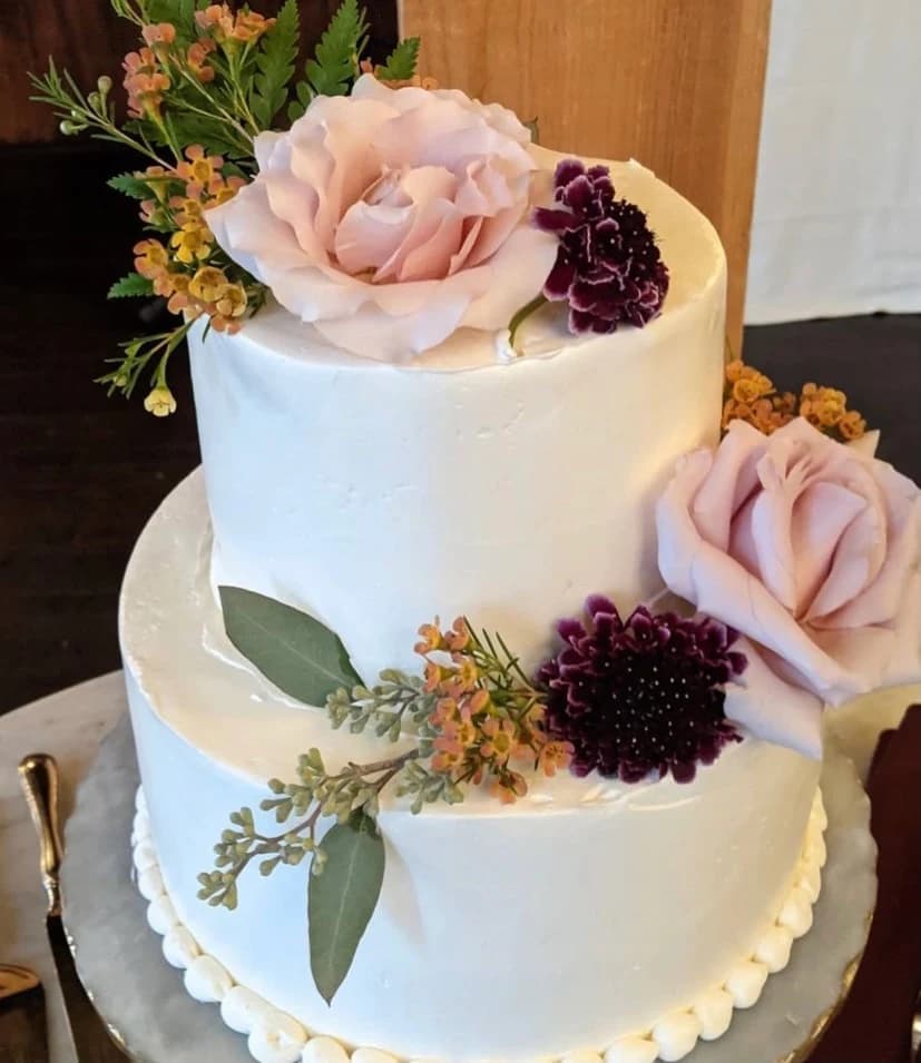 White wedding cake with burgundy and blush blooms