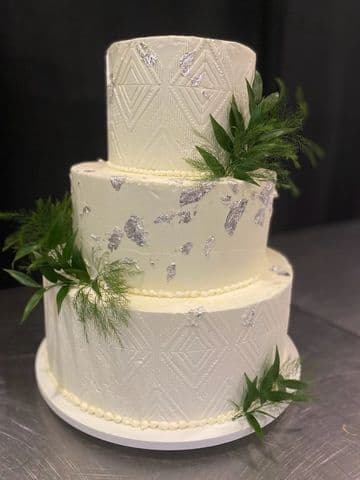 Two-tier white wedding cake trimmed with eucalyptus